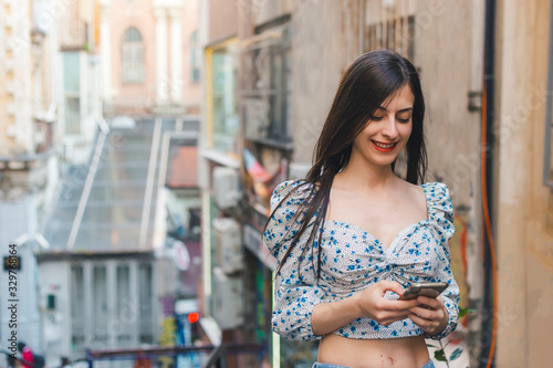 Cheerful brunette woman looking to her mobile phone and smiling in a street copy space