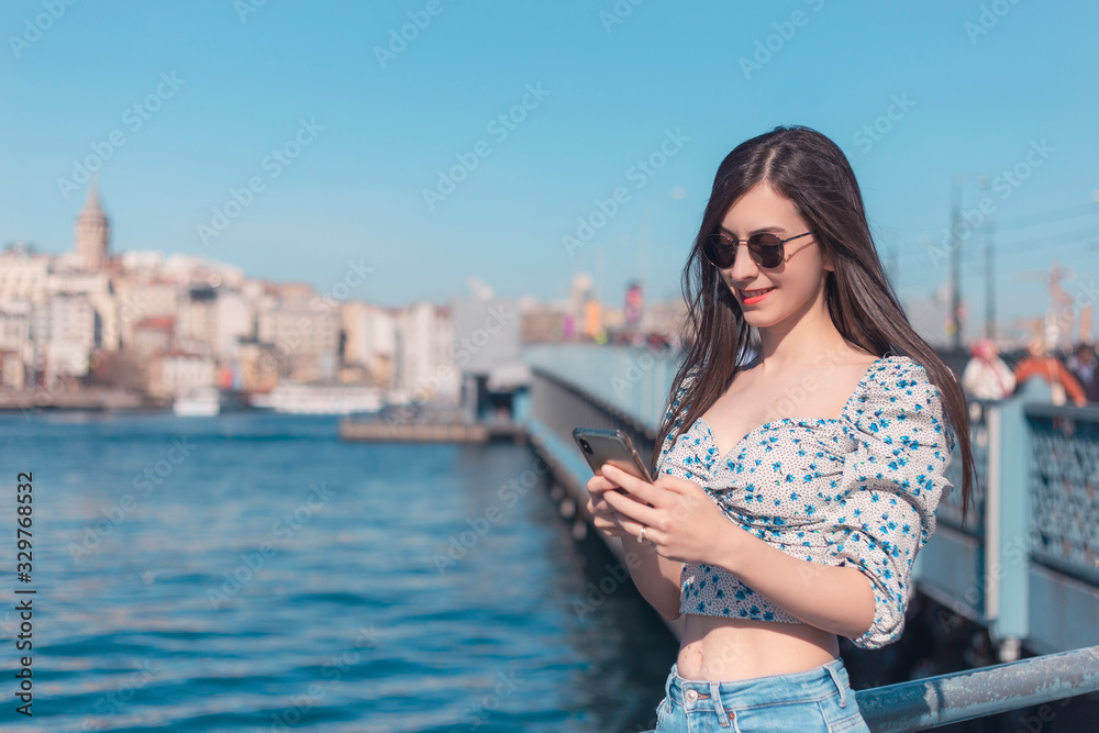 Attractive young brunette woman looking to mobile phone with her sunglasses in Istanbul copy space