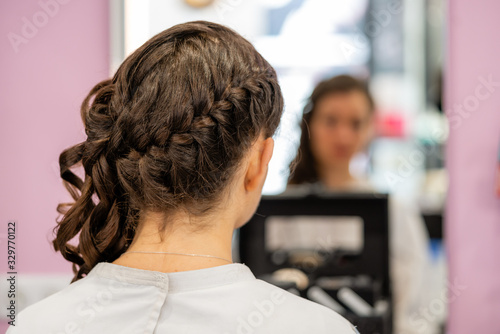 Details of the hairstyle of a young woman with braids, curls and flowers