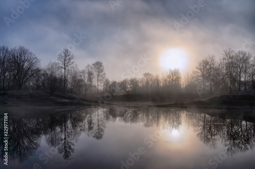 Early morning, fog glade, grass and trees in hoarfrost and a lake house. © ostapenkonat