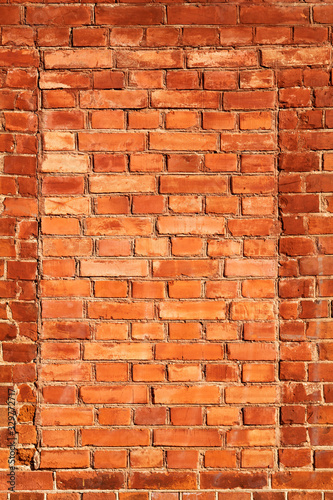 Old red brick wall with brick filled window.