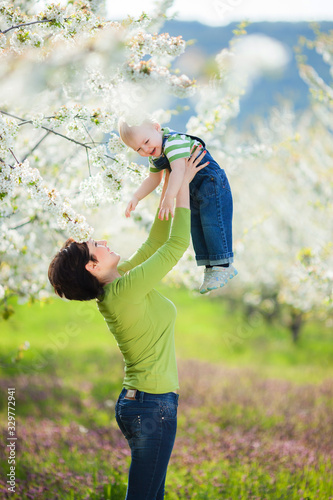 Happy woman and child in the blooming spring garden.