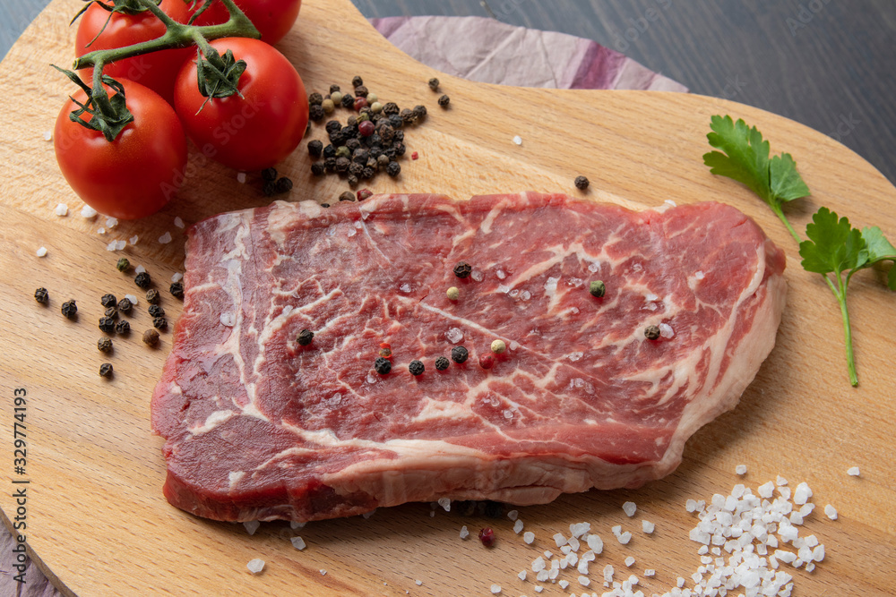 Raw beef steak with spices on a dark board. View from above. Raw beef steak with spices on a dark board. View from above.