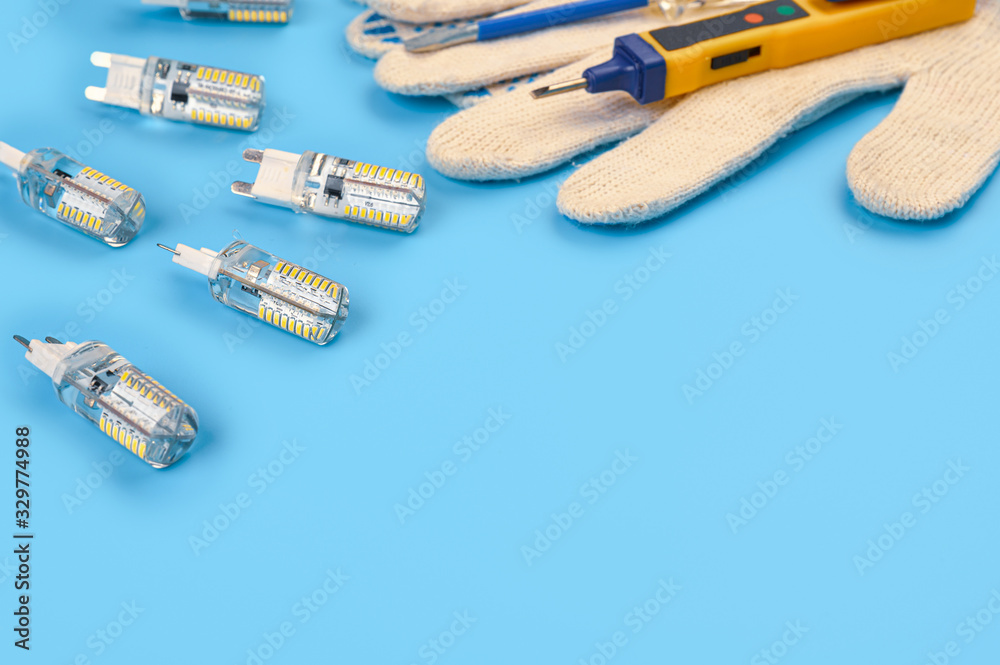 .LED lamps with an electrician tool on a blue background. .LED lamps with an electrician tool on a blue background.