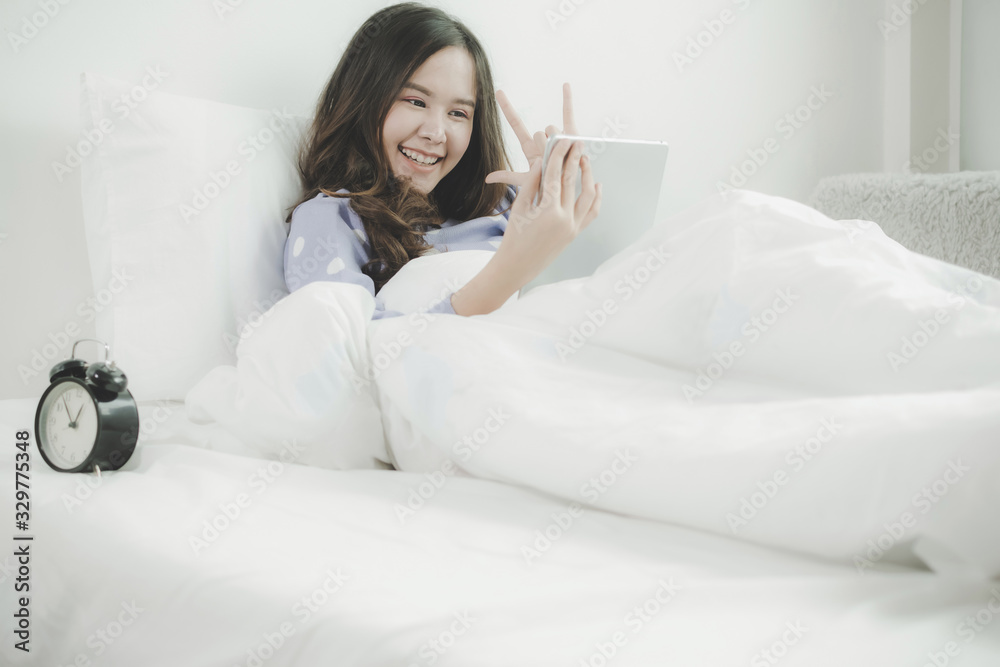 happy young asian pretty woman smiling take selfie and video call chat on digital mobile tablet and lying on bed at home at night, video call connection, internet, telecommunication technology concept happy young asian pretty woman smiling take selfie and video call chat on digital mobile tablet and lying on bed at home at night, video call connection, internet, telecommunication technology concept