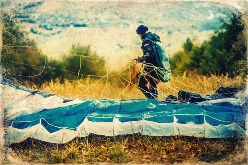 Paragliding in the mountains, paraglider on the ground, old photo effect. © jozefklopacka