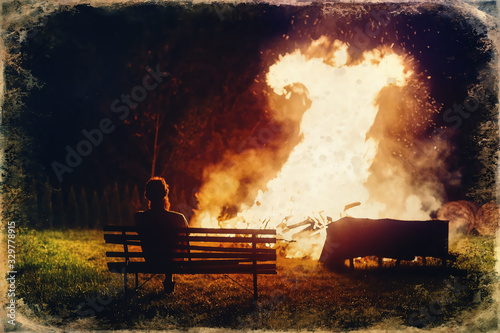 Man sitting by the fire and looking to the flame, old photo effect.