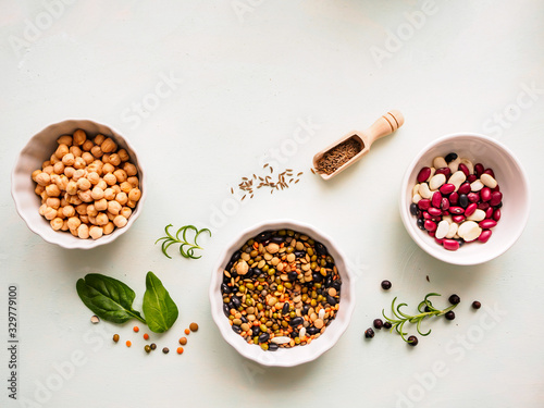 Verschiedene getrocknete Hülsenfrüchte in weißen Schüsseln und Gewürze auf einem Tisch, Draufsicht, pflanzliches Eiweiß, vegane Ernährung photo