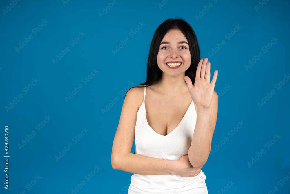Front view of laughing girl showing palm isolated on blue background Front view of laughing girl showing palm isolated on blue background