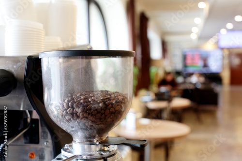 Coffee machine in the cafe, coffee beans before grinding. View of the interior with tables, cozy atmosphere, selective focus © Oleg