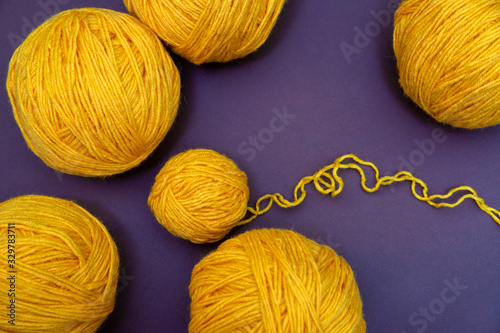 Yellow Balls of yarn for knitting on the pirple background photo