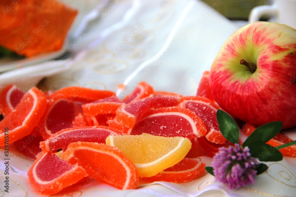 Clover flower, orange marmalade slices and red apple. picnic in nature in a city park