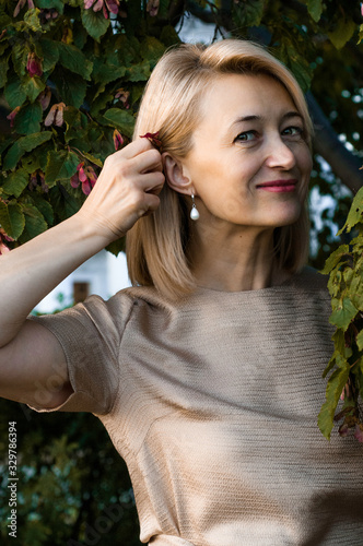 Middle-aged blond woman with a smile in a summer park photo