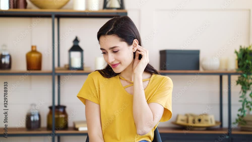 Modest girl touching hair and smiling at home Modest girl touching hair and smiling at home