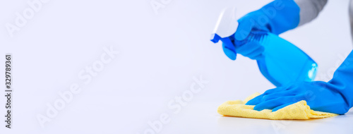 Εκτύπωση καμβά Young woman housekeeper is doing cleaning white table in apron with blue gloves, spray cleaner, wet yellow rag, close up, copy space, blank design concept