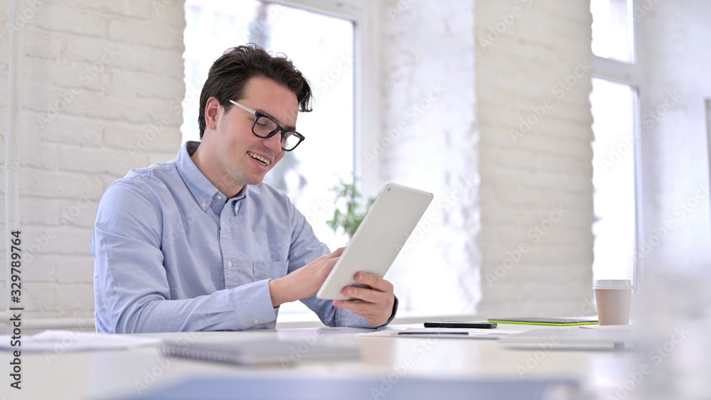 Cheerful Working Young Man using Tablet in Modern Office