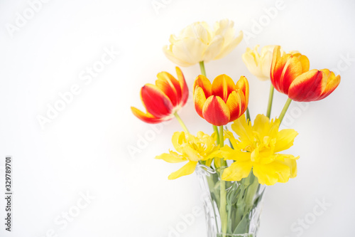 Fototapeta Naklejka Na Ścianę i Meble -  Tulip flower in glass vase with picture frame place on white wooden table background against clean wall at home, close up, Mother's Day decor concept.