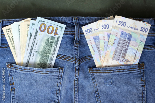 Banknotes of different denominations in the pocket of women's jeans, background. Concept, American dollars and Ukrainian hryvnias