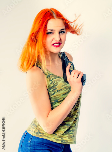 Young woman gangster with gun on a light background.Portrait of beautiful redhead girl in hat with gun. Red beast