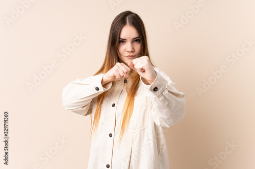 Young caucasian woman isolated on beige background with fighting gesture