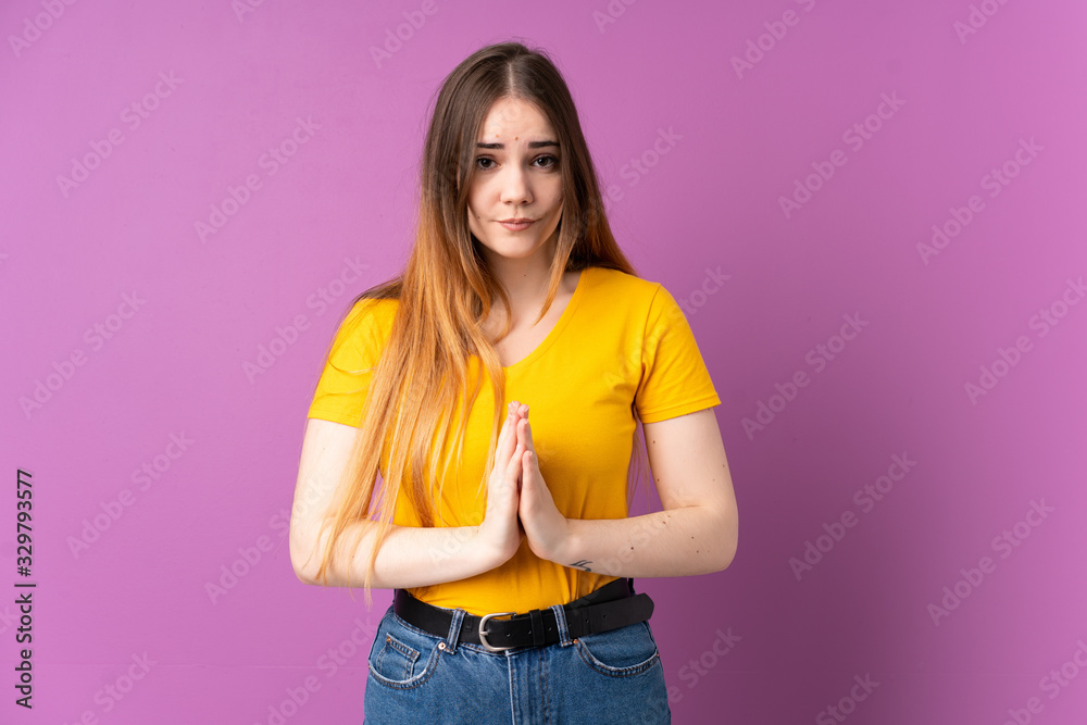 Young caucasian woman isolated on purple background keeps palm together. Person asks for something Young caucasian woman isolated on purple background keeps palm together. Person asks for something