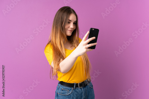 Young caucasian woman isolated on purple background making a selfie