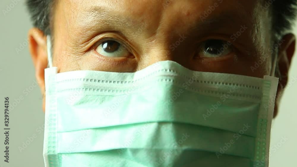 Man wearing hygienic mask rolling his eyes , indoor Chiangmai Thailand Man wearing hygienic mask rolling his eyes , indoor Chiangmai Thailand