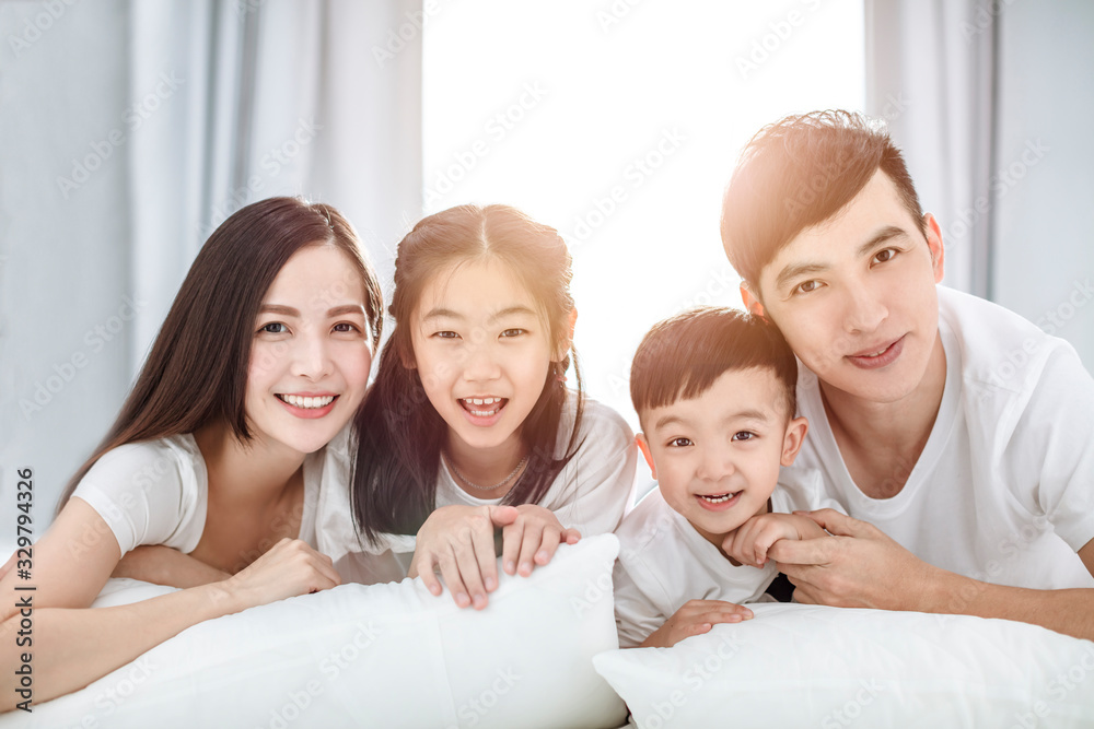 Happy family lying on bed together in the bedroom Happy family lying on bed together in the bedroom