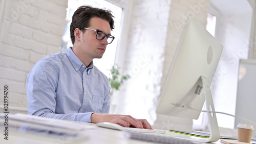 Fotografie Working Young Man using Laptop in Modern Office
