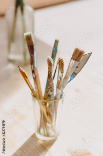  A brush in a glass on a light background backlit by the rays of the sun. 