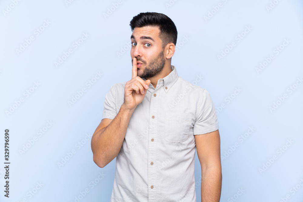Young handsome man with beard over isolated blue background doing silence gesture