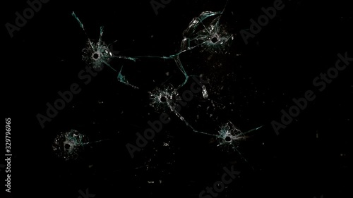 Shot Glass breaking with bullet holes on black background photo