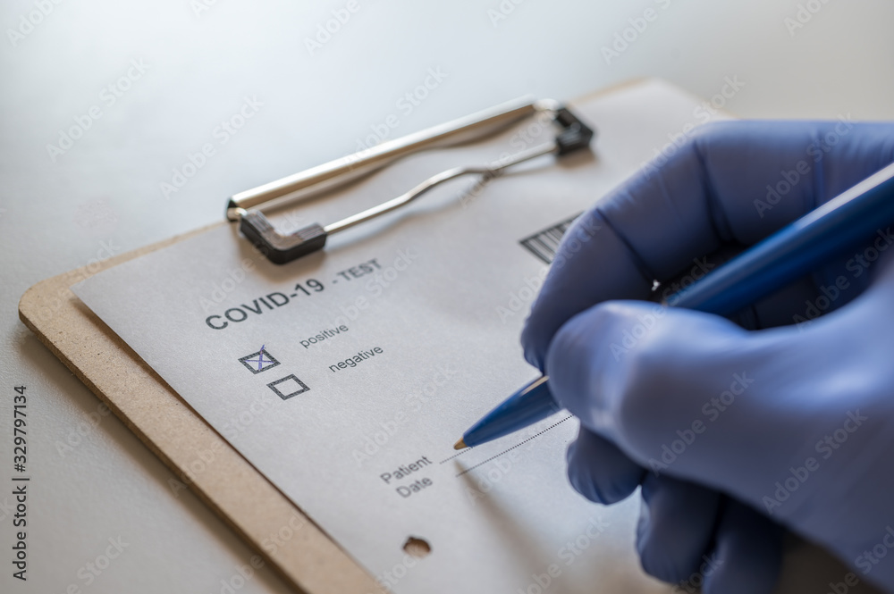 Arzt füllt positiven COVID-19 Test eines Patienten aus - obrazy, fototapety, plakaty 