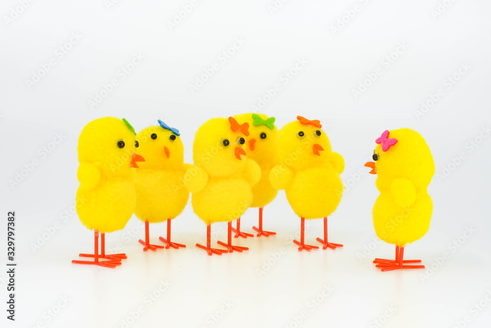 Cute yellow model chicks in a group. One chick is talking to the rest of the group against a plain white background Cute yellow model chicks in a group. One chick is talking to the rest of the group against a plain white background