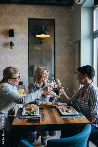 women friends having lunch break in restaurant, making a toast