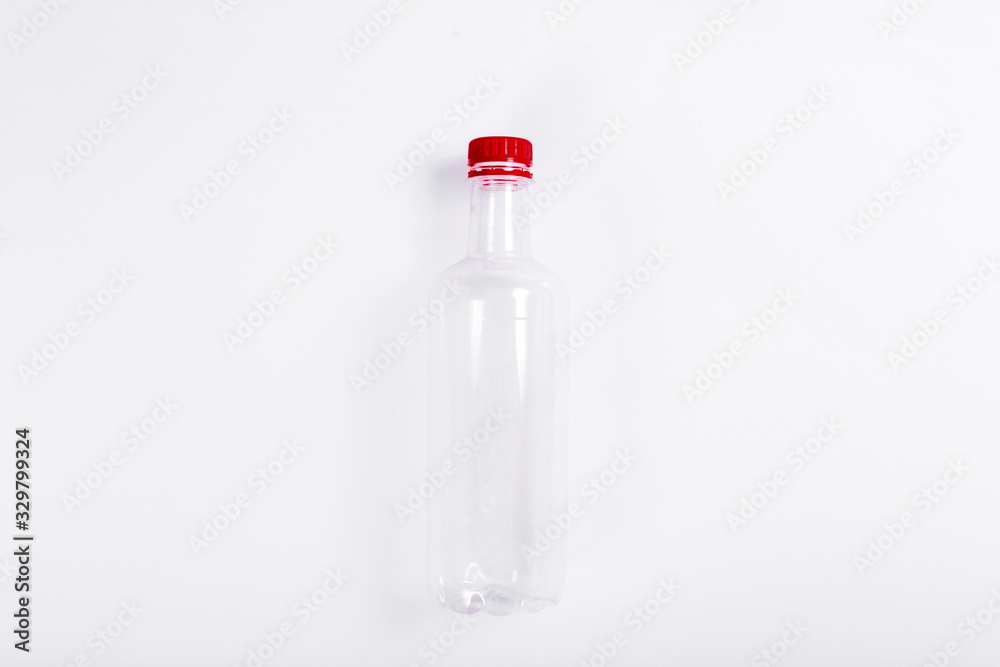 Empty transparent plastic bottle with a red cap on a white background