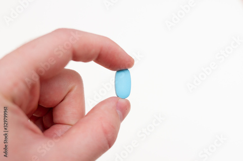 Man hand with blue capsule tablet on white background