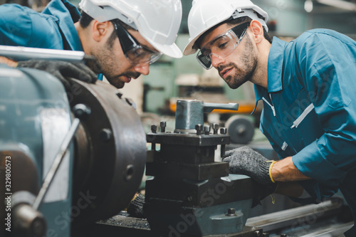 Two maintenance engineers discuss inspect relay checking machinery and repair system in a factory. They work a heavy industry manufacturing factory. photo