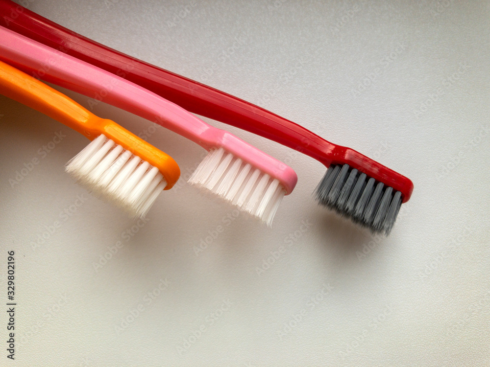 three multi-colored toothbrushes on a white background three multi-colored toothbrushes on a white background