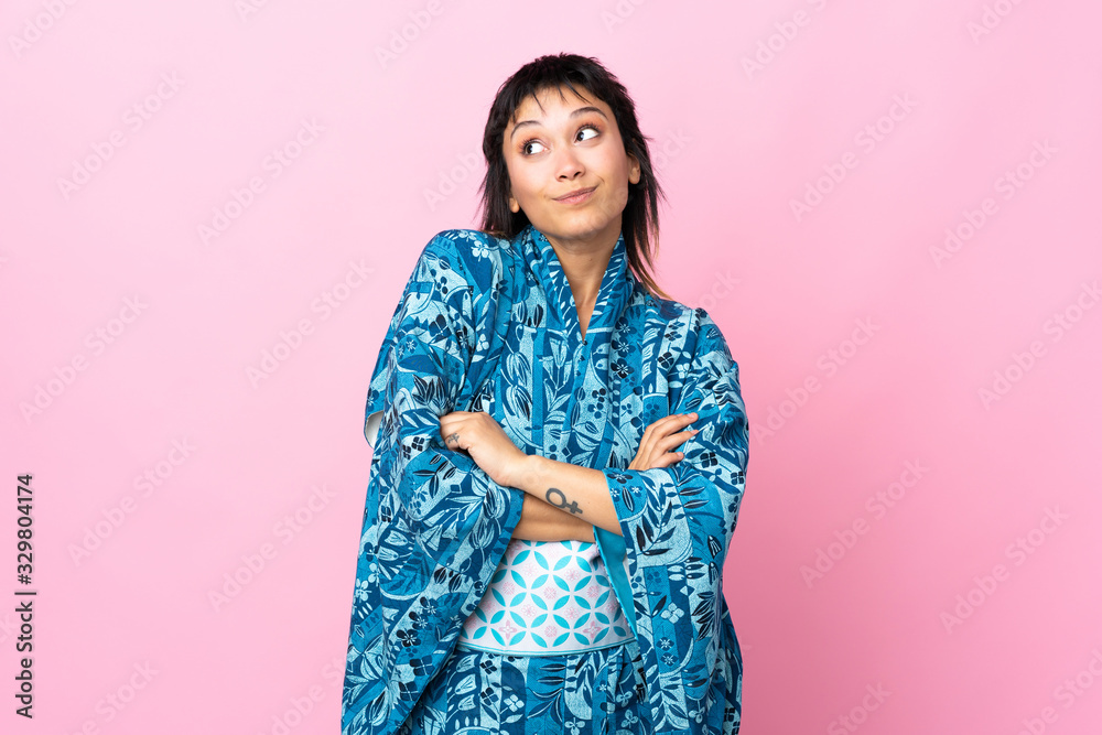 Young woman wearing kimono over isolated blue background making doubts gesture while lifting the shoulders Young woman wearing kimono over isolated blue background making doubts gesture while lifting the shoulders