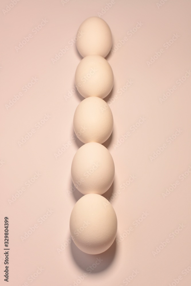 A vertical line in the center of oval chicken eggs lined up by a chain in a bed pink peach color. A vertical line in the center of oval chicken eggs lined up by a chain in a bed pink peach color.