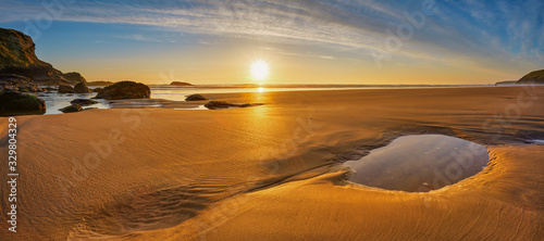 Schöner unberührter Strand in Cornwall, der im Sonnenlicht golden leuchtet.