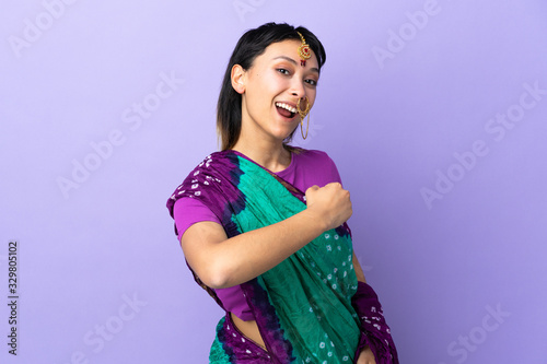 Indian woman isolated on purple background celebrating a victory