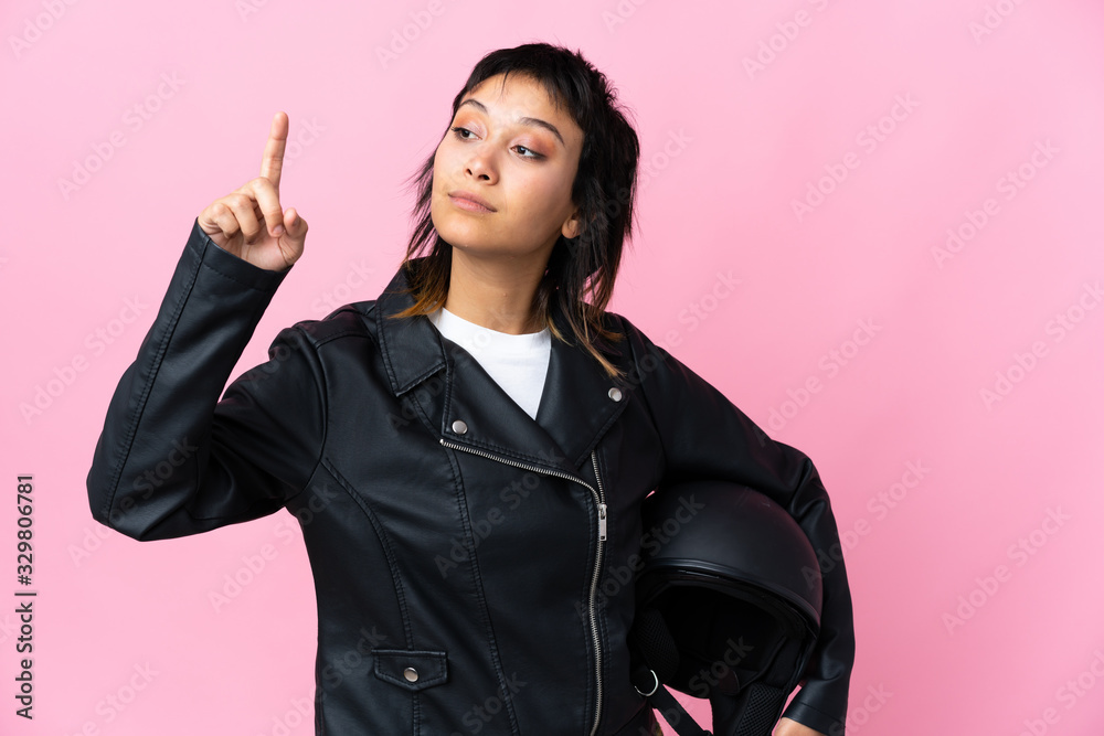Young Uruguayan woman holding a motorcycle helmet over isolated pink background touching on transparent screen Young Uruguayan woman holding a motorcycle helmet over isolated pink background touching on transparent screen