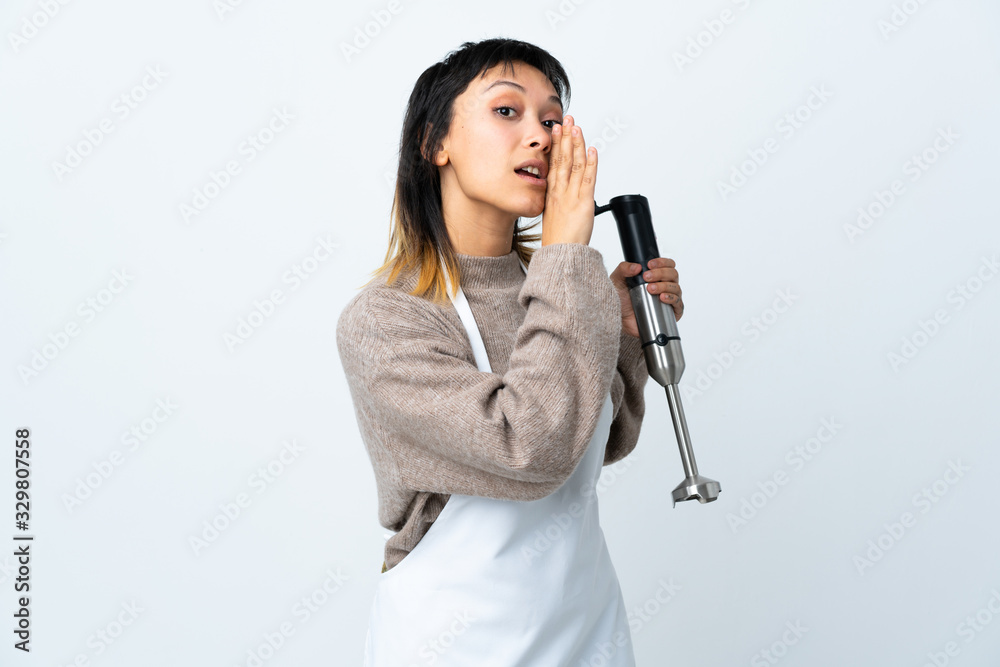 Chef Uruguayan girl using hand blender over isolated white background whispering something Chef Uruguayan girl using hand blender over isolated white background whispering something