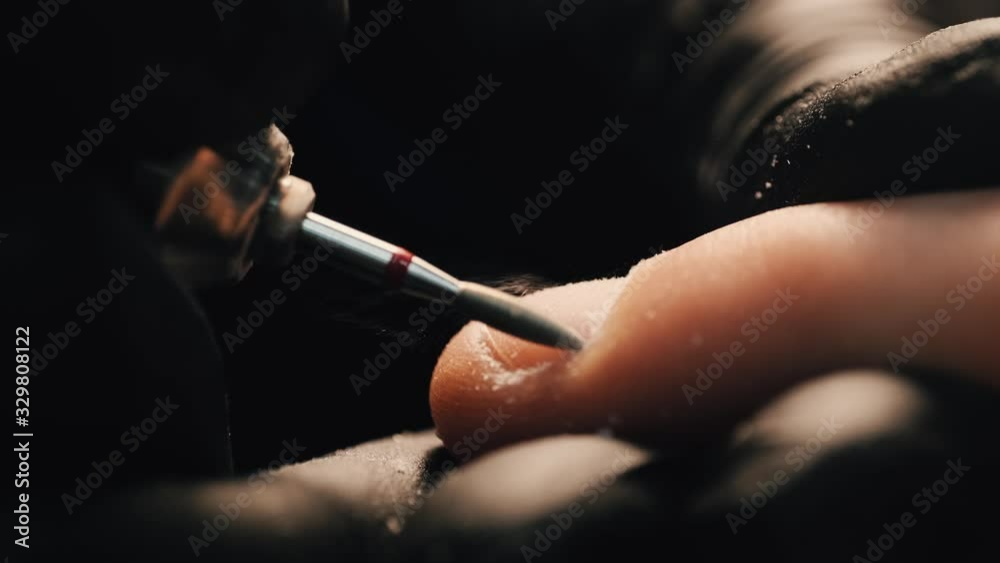 Men's manicure. Professional manicure for man by manicure machine. A man receiving a manicure in the beauty salon. Beautician master trimming and removes cuticles.
