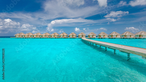 Panoramic landscape of Maldives beach. Tropical panorama  luxury water villa resort with wooden pier or jetty. Luxury travel destination background for summer holiday and vacation concept.