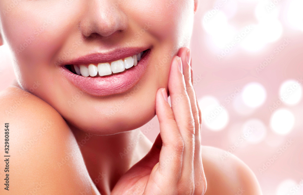 Obraz premium Closeup shot of young beautiful woman face portrait with healthy skin. Pretty girl smiling to you on an abstract background with blurred lights