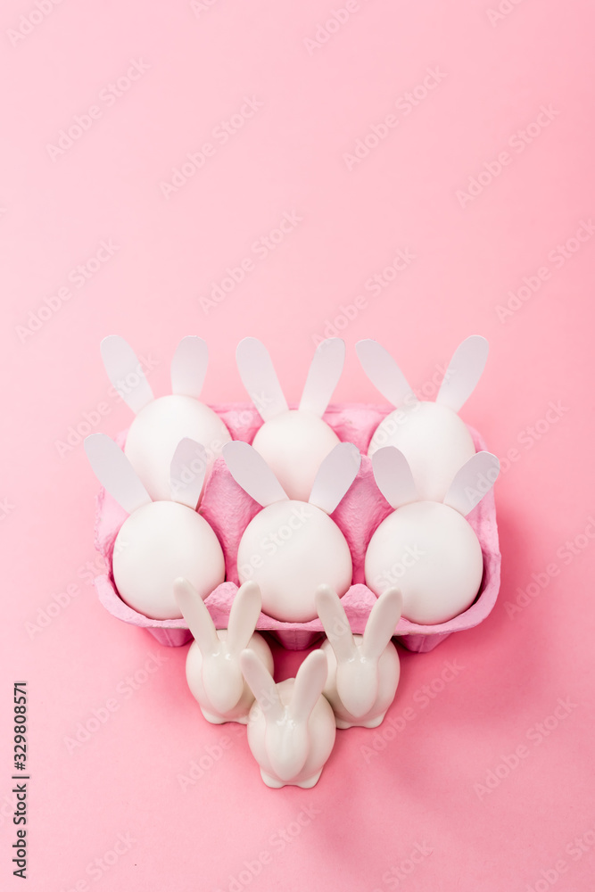 High angle view of Decorative easter rabbits with egg tray on pink background High angle view of Decorative easter rabbits with egg tray on pink background