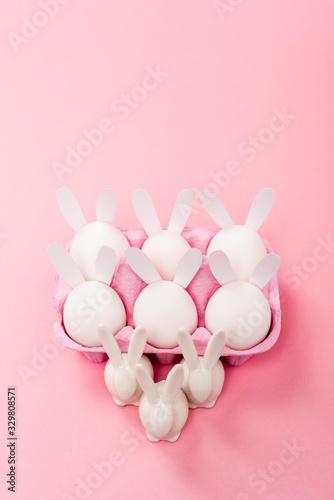 High angle view of Decorative easter rabbits with egg tray on pink background